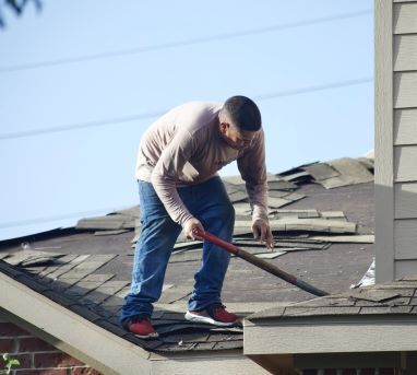 Man on a roof replacing roof shingles